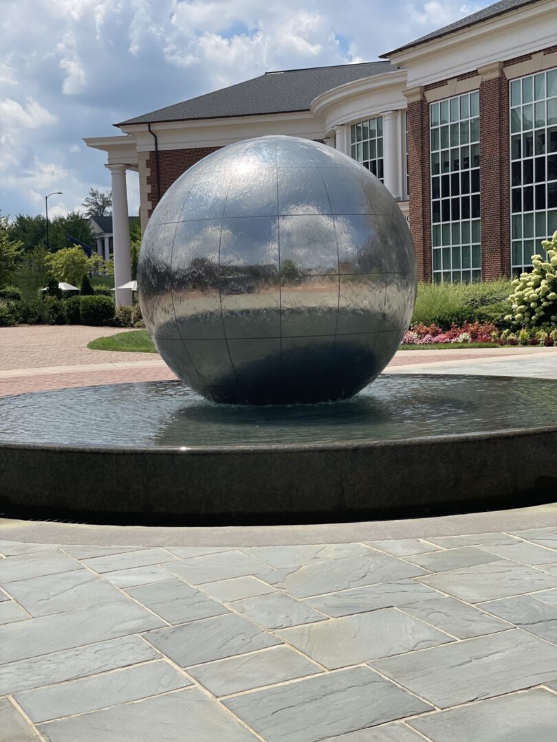 A large metal ball fountain in front of a building.