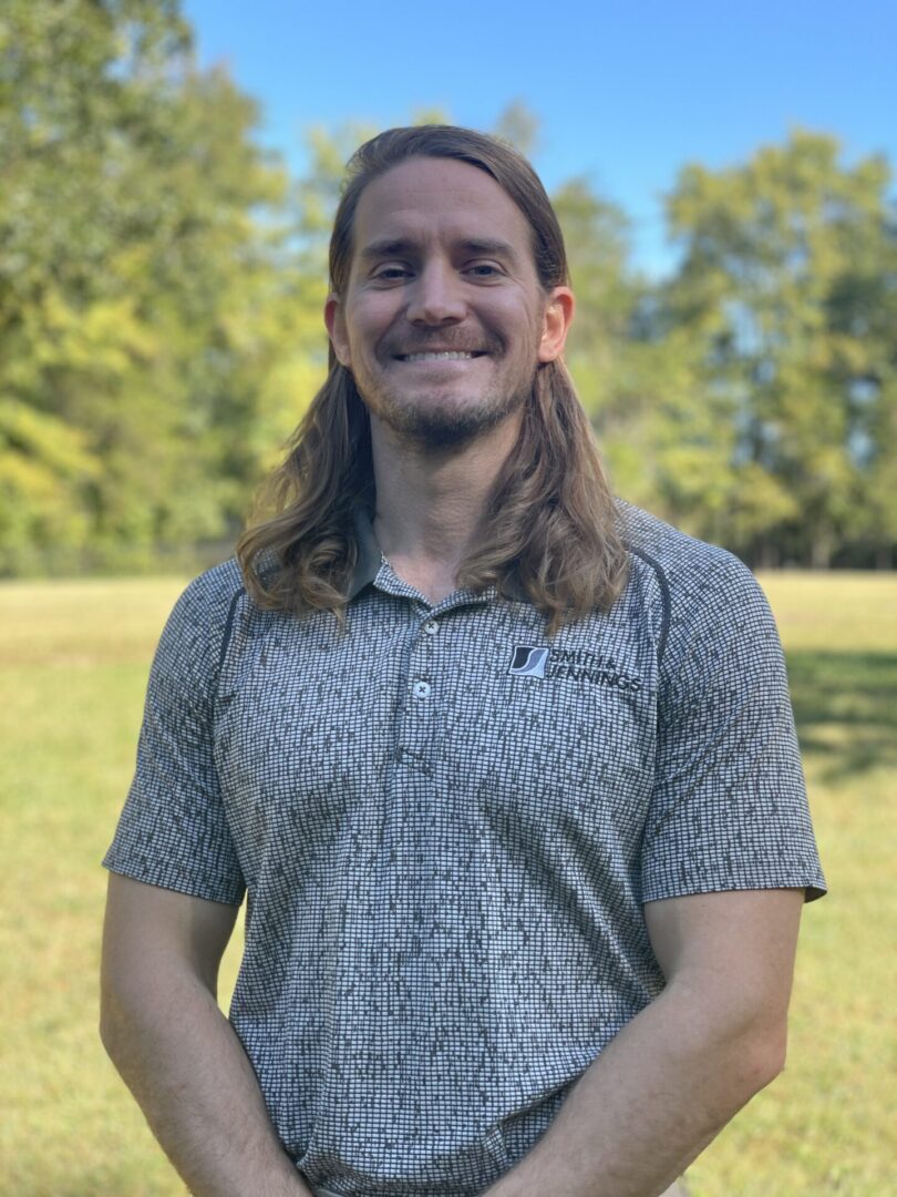 A man with long hair standing in the grass.