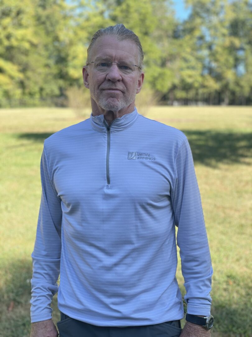 A man standing in the grass wearing a long sleeve shirt.