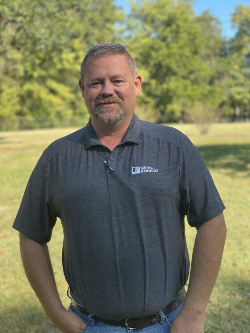 A man standing in the grass wearing a blue shirt.